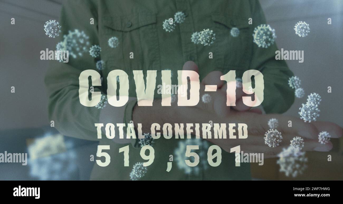 Image of word covid-19 and scientific information with man disinfecting hands in office Stock Photo