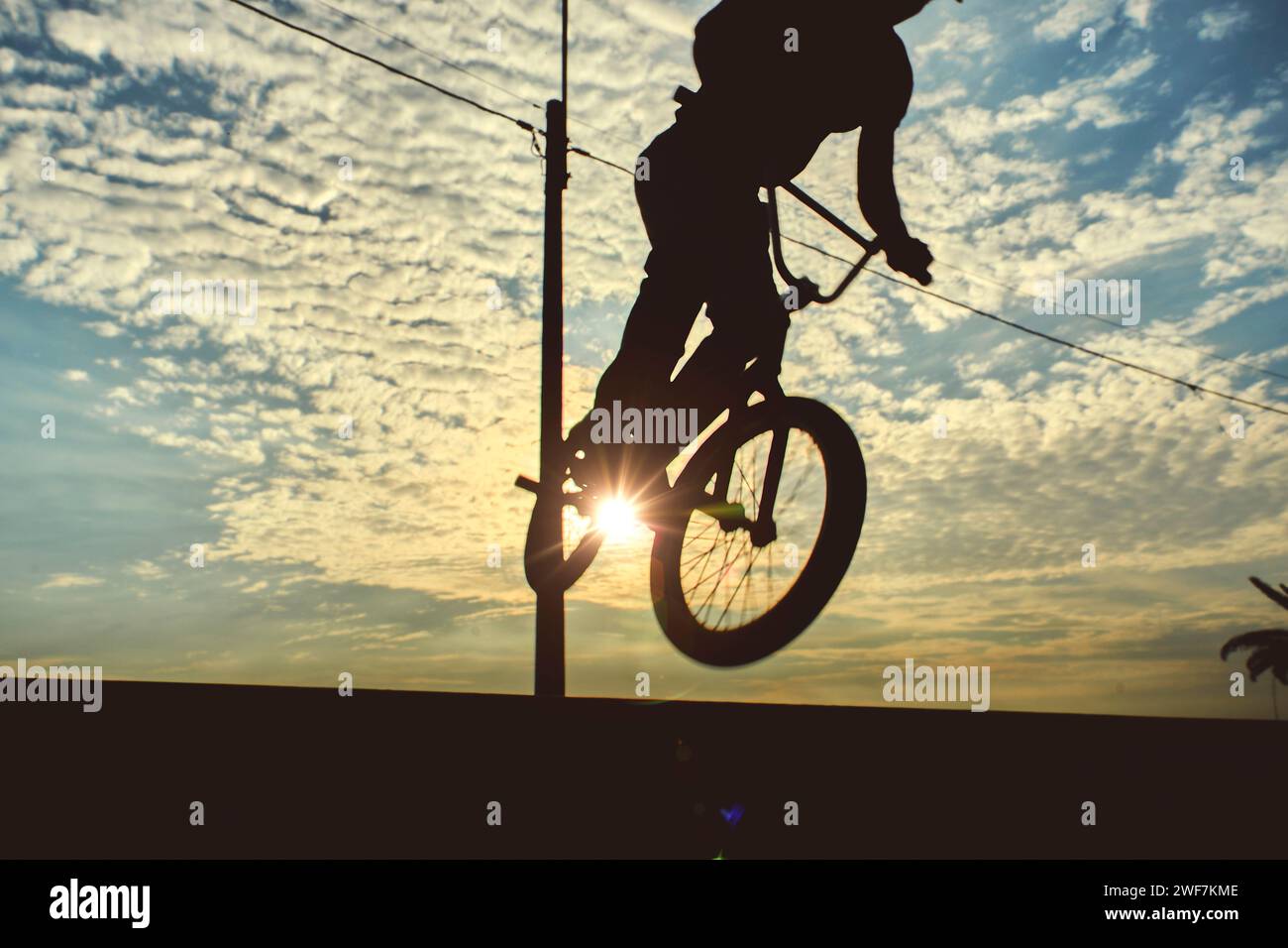 Silhouette unrecognizable Young man doing ramp jump stunt on bmx bicycle on sunset Stock Photo