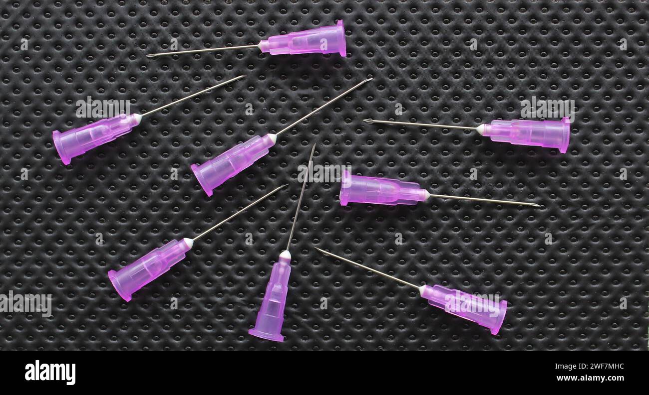 Needles for a medical syringe without caps on a black rubberized surface Stock Photo
