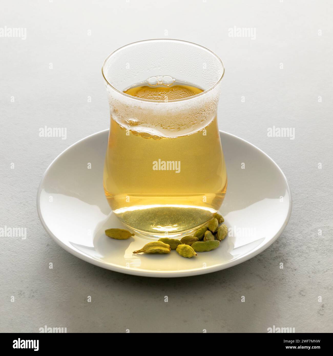 Tea glass with fresh made hot green Cardamon tea and seed pods close up Stock Photo