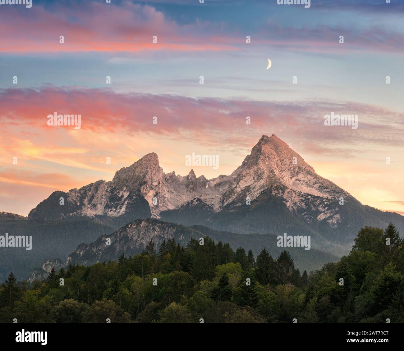 A majestic mountain formation, the Watzmann in Bavaria, Germany, with a colorful sunset sky and woodlands in the foreground Stock Photo