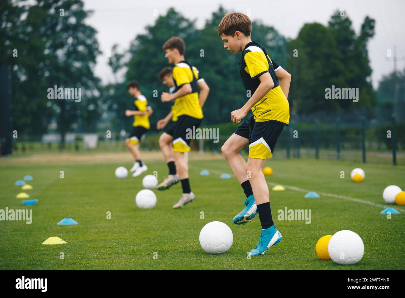 Football Academy For Teens. Youth Football Player in Soccer Ball Control Drills. Young Boys in the Football Team At Workout. Ambitious Young Athletes Stock Photo