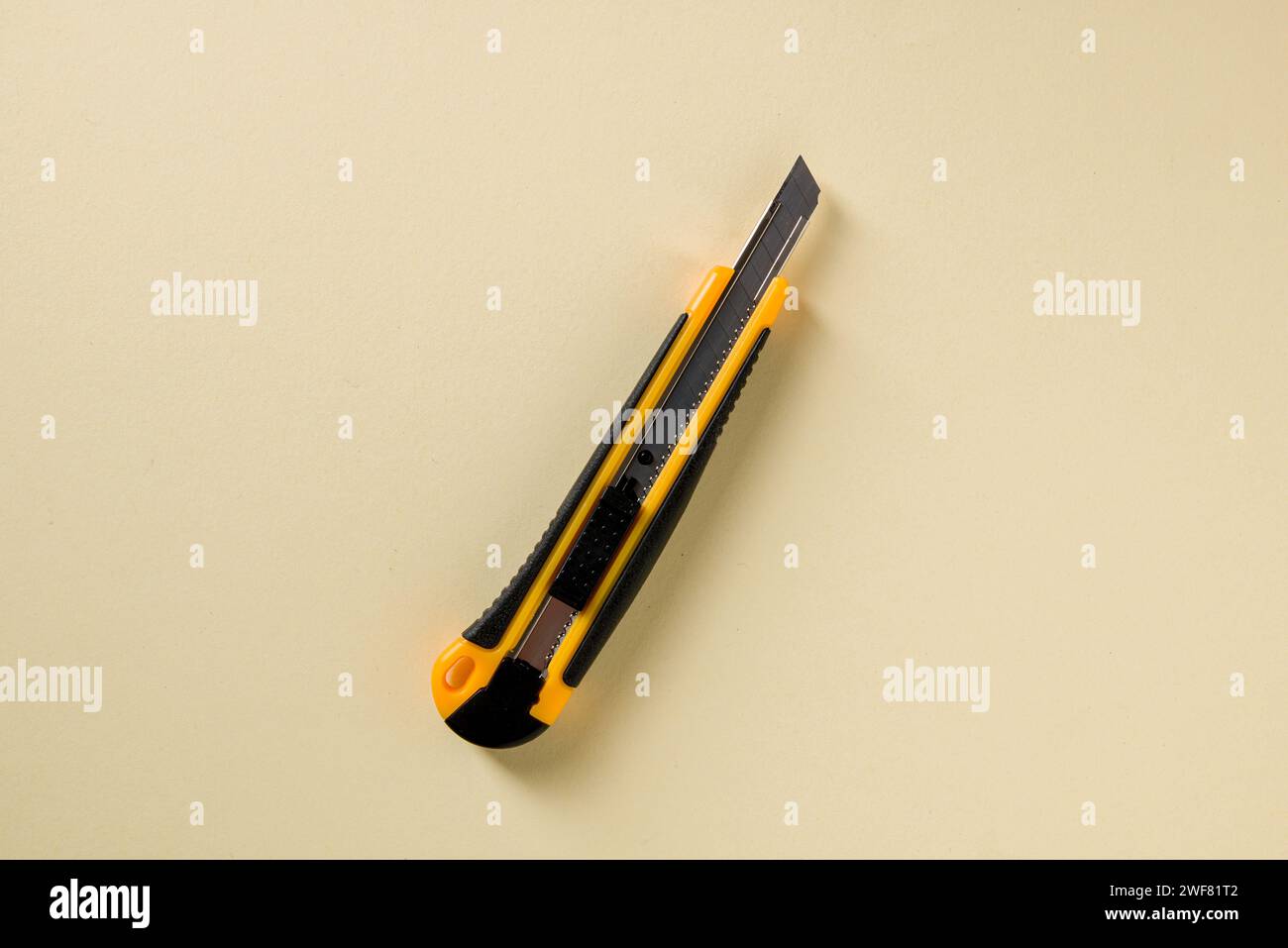 Utility knife with yellow and black handle on a yellow background Stock Photo