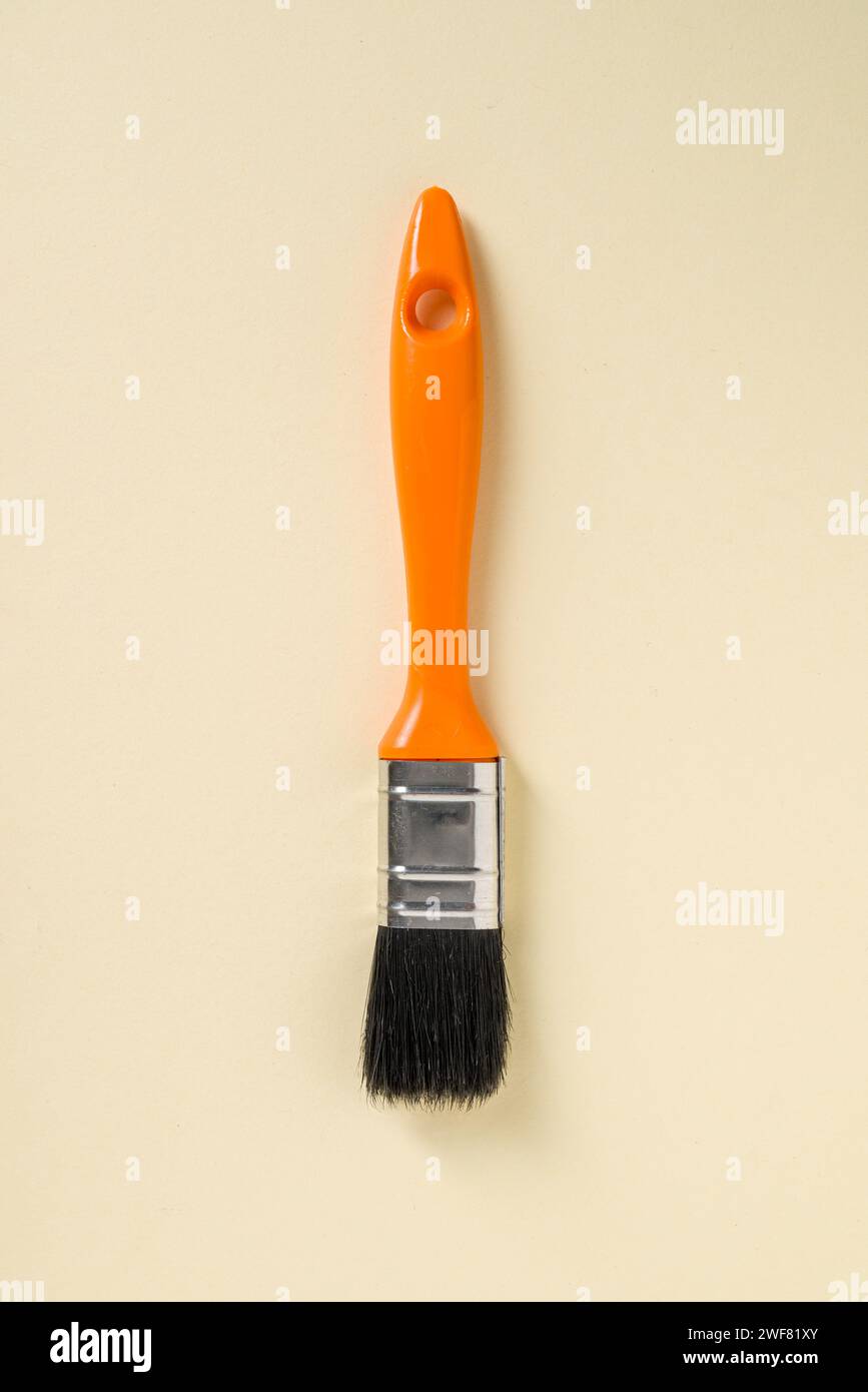Touch-up paint brush with orange handle on yellow background Stock Photo