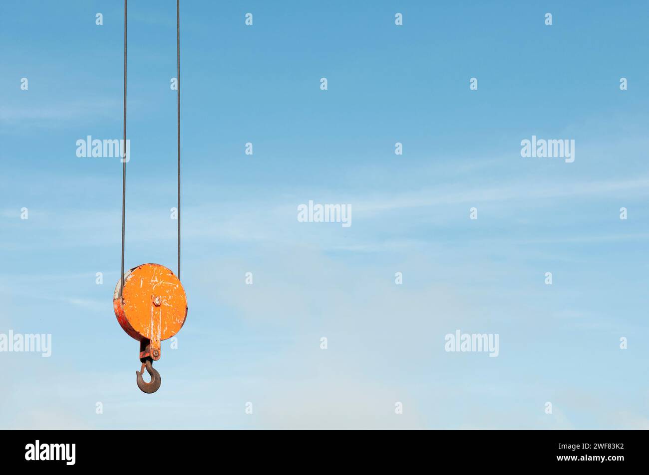 An empty industrial crane hook suspended against a blue evening sky Stock Photo