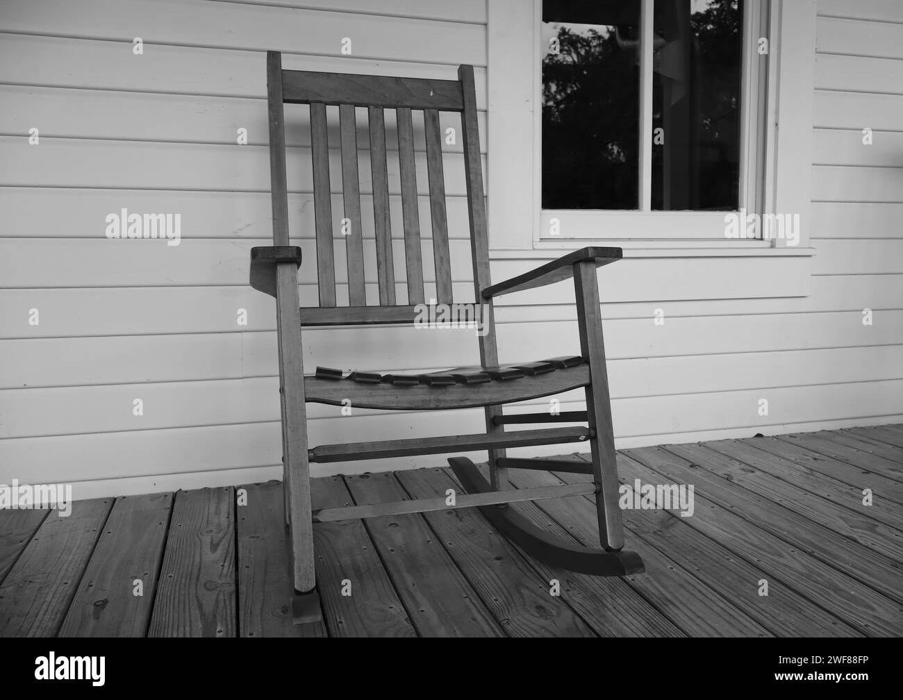 A cozy wooden rocking chair adorns a charming porch Stock Photo