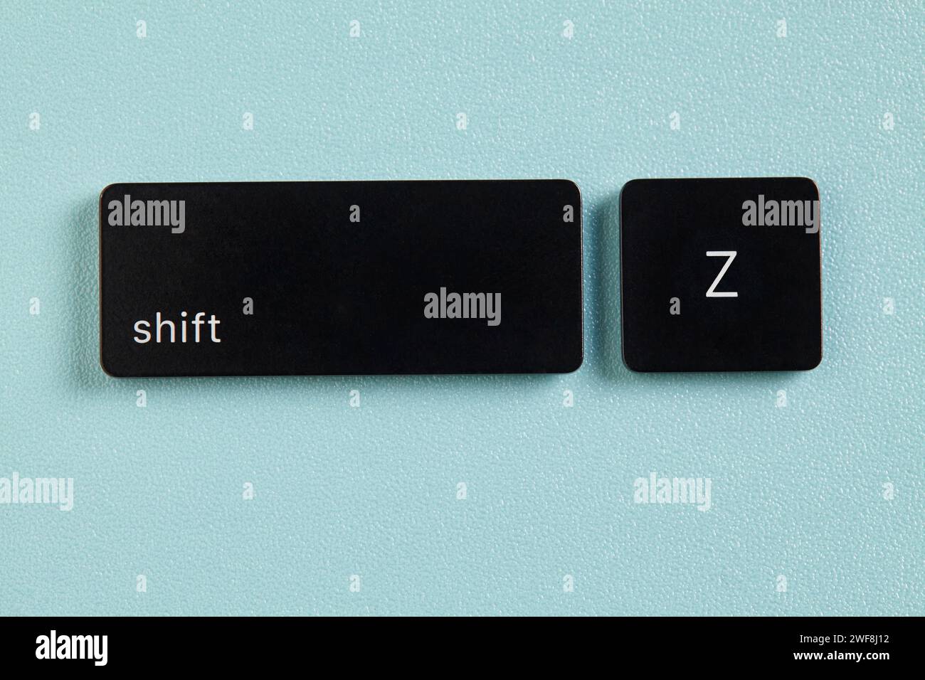 Shift key and Z key detached from keyboard on blue background Stock Photo