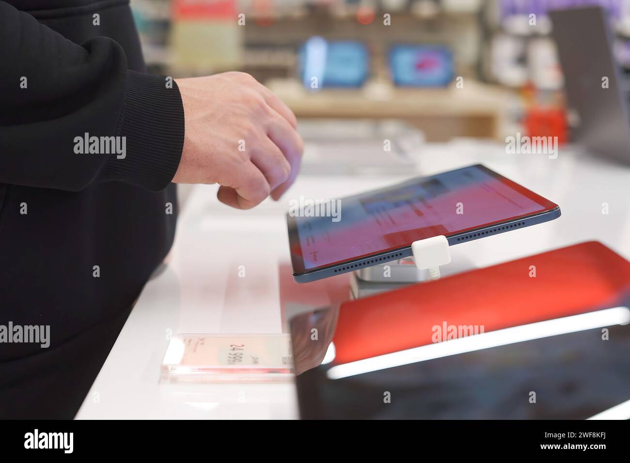 A white man uses a digital tablet in an electronics store. Stock Photo