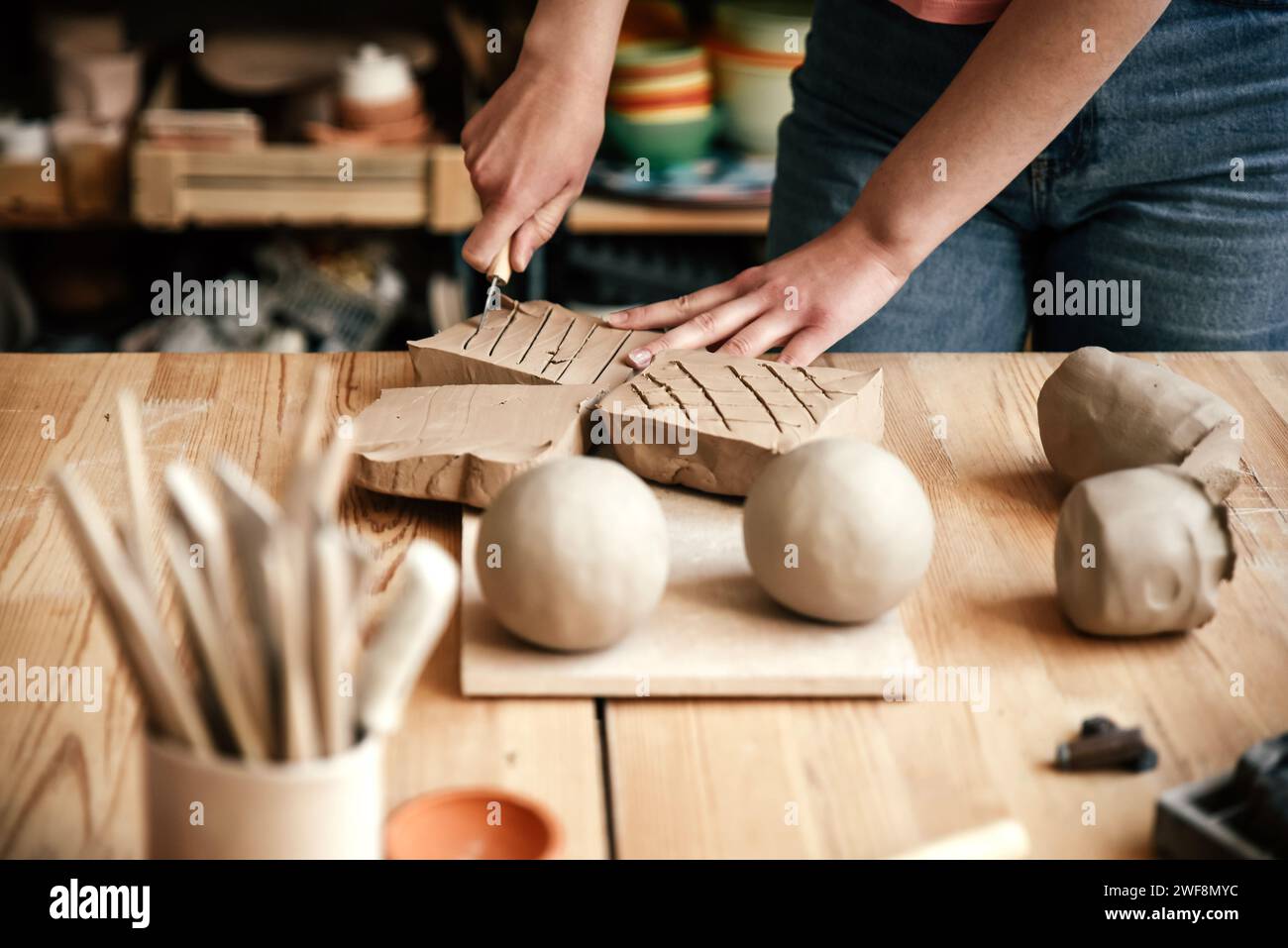 Potter cuts piece of clay with knife to soften it. Stock Photo
