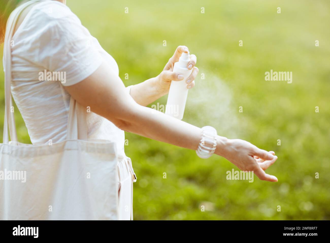 Sunscreen Outside Summer time. Closeup on female in white shirt using sunscreen in the ...