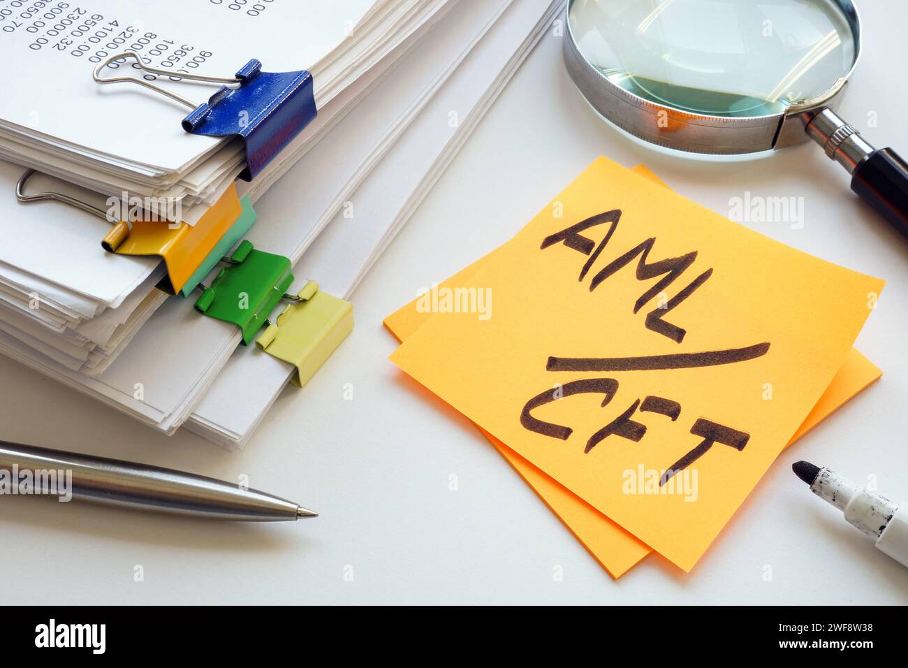 Stack of papers, magnifying glass and abbreviation AML CFT anti-money laundering and combating the financing of terrorism. Stock Photo