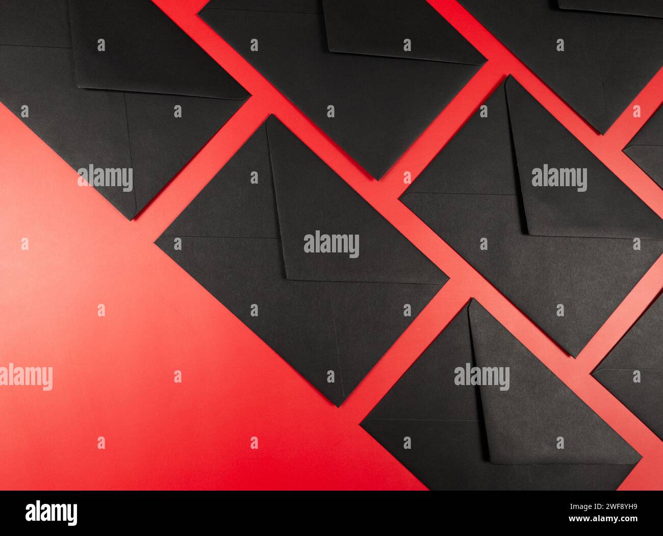 Top view of black envelopes on red background. Post flat lay, copy space. Stock Photo
