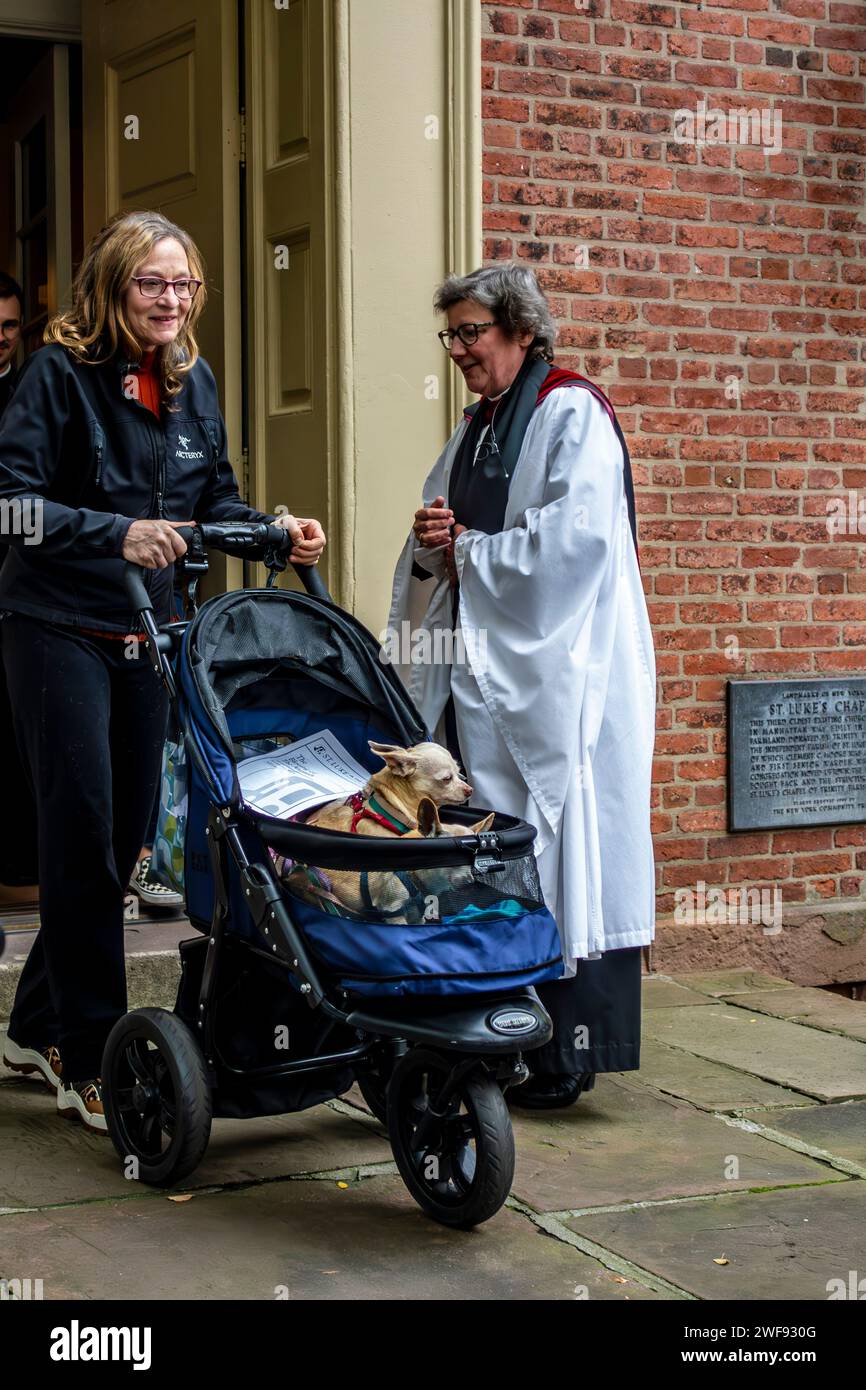 The Reverend Caroline Stacey speaking to a parishioner with dogs in a carriage at the Blessing of the Animals, St. Luke in the Fields, New York City Stock Photo