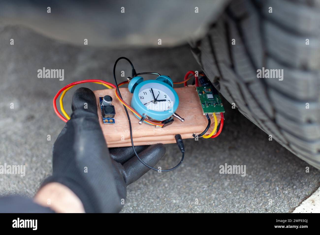 mobster placing a time bomb under vehicle Stock Photo