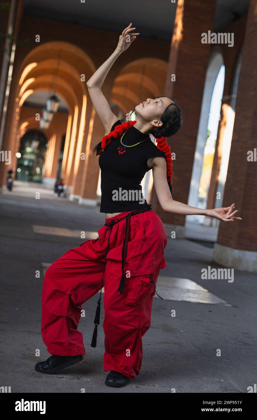 An urban female dancer in red pants captures the essence of oriental dance through her poised and flowing movements. Stock Photo
