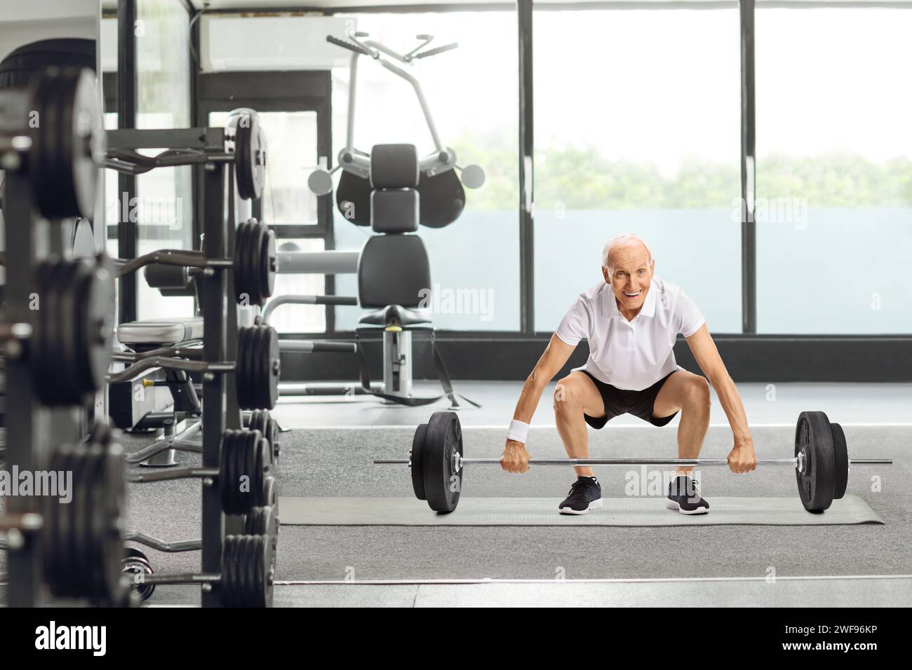 Senior man lifting a barbell at a gym Stock Photo