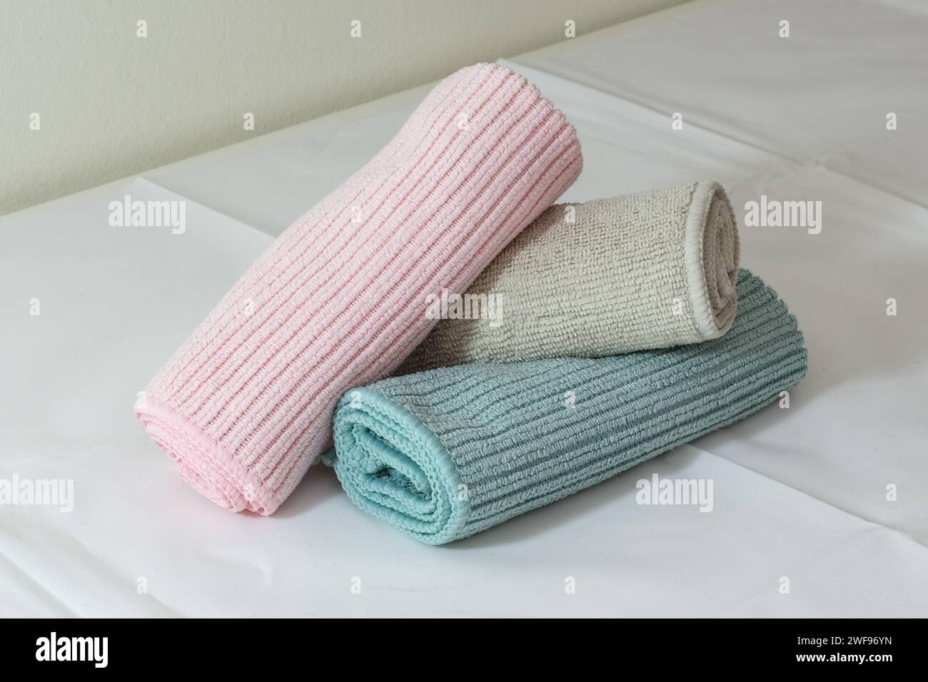 Microfiber cleaning cloths in pink, beige and green colors on a table ready for cleaning. White background Stock Photo