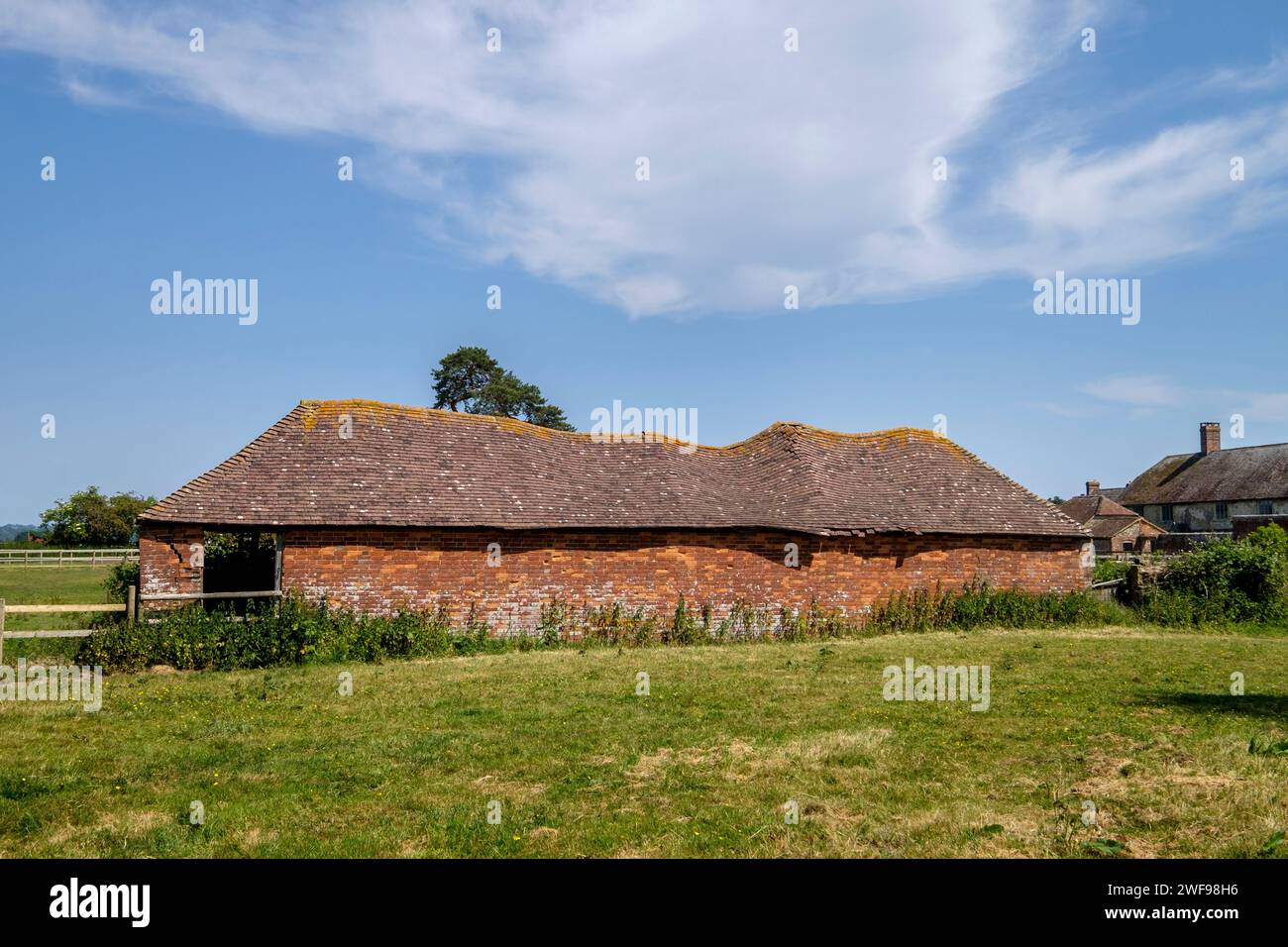 An old barn with a very wobbly tiled roof West Sussex Stock Photo