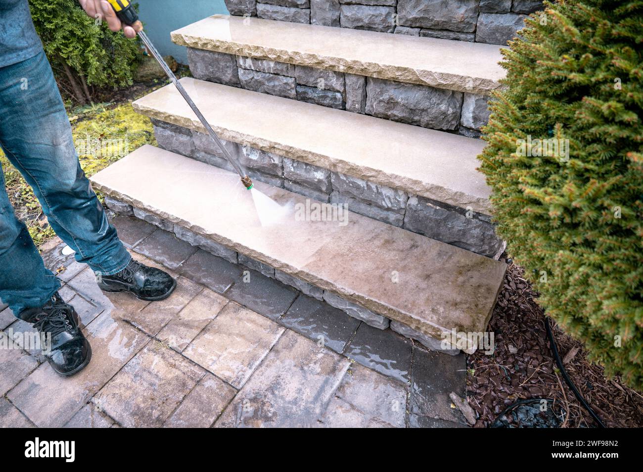 Man cleaning outdoor dirty porch stairs with a power wash machine Stock