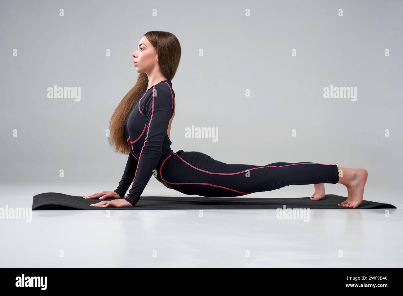 Focused young woman in activewear stretching body indoors. Side view of ...
