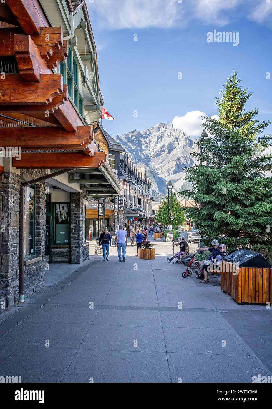 Shops and pedestrians on Banff Avenue with Cascade mountain in the background in Banff, Alberta, Canada on 8 June 2023 Stock Photo