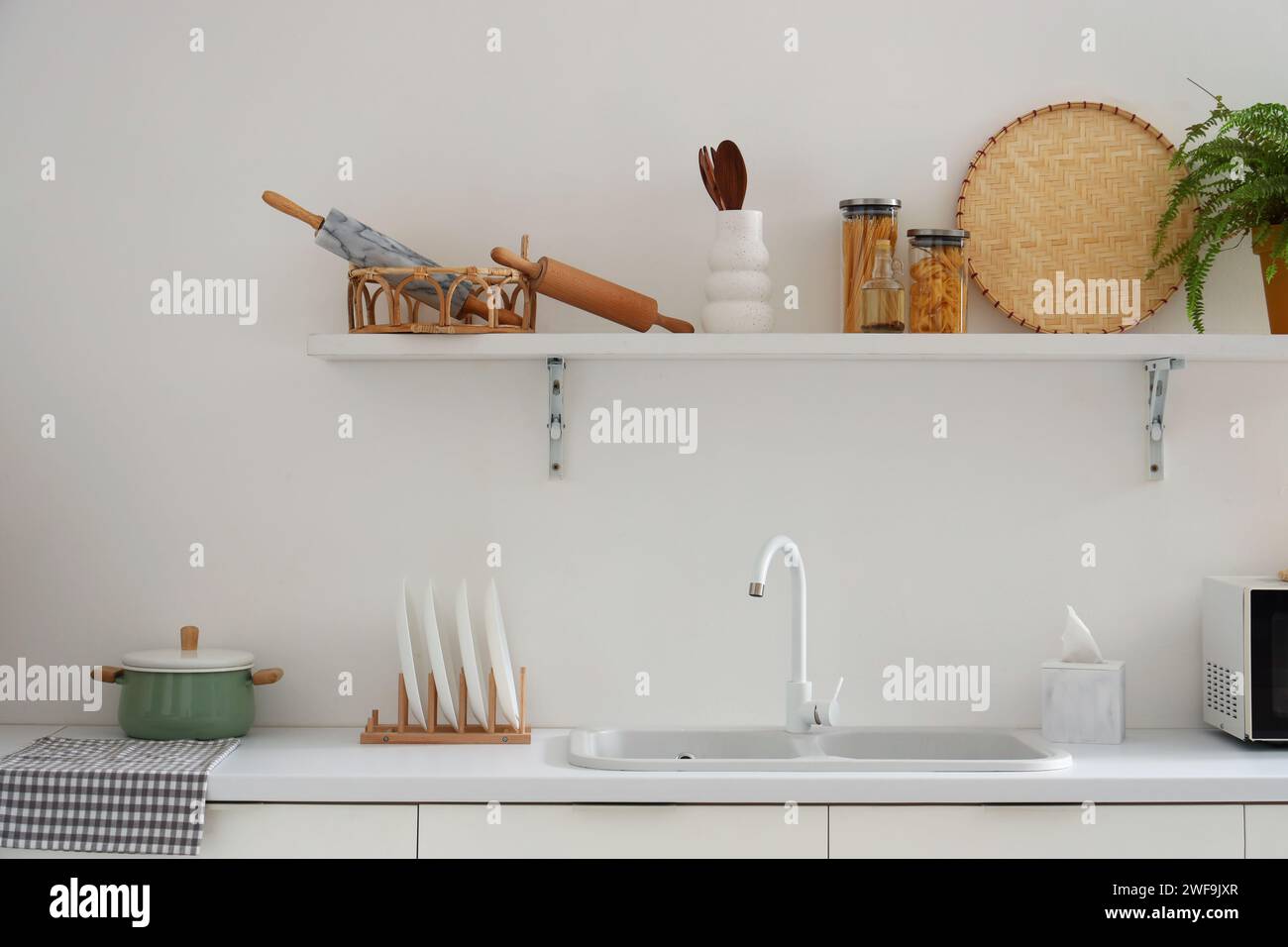 Interior of modern kitchen with utensils and sink on white counters ...
