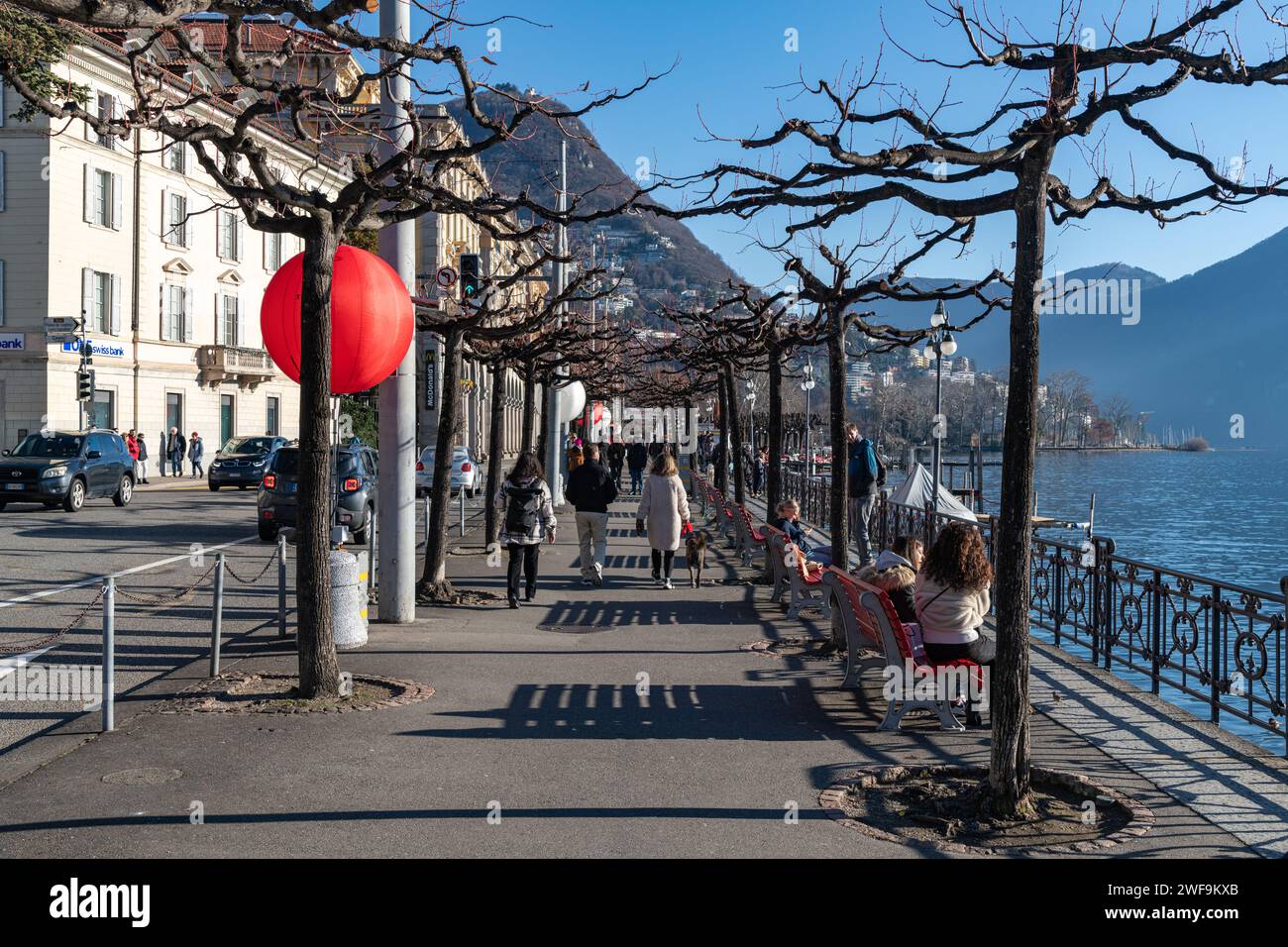 People / Tourists walking along the promenade by Lake Lugano in Switzerland Stock Photo