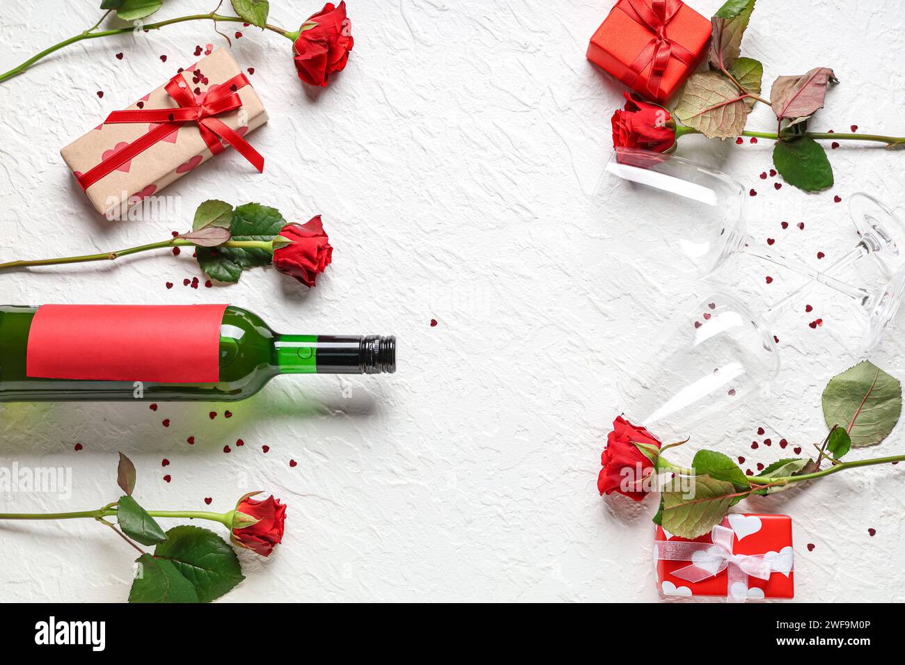 Bottle of wine with glasses, gift boxes and red roses on white ...