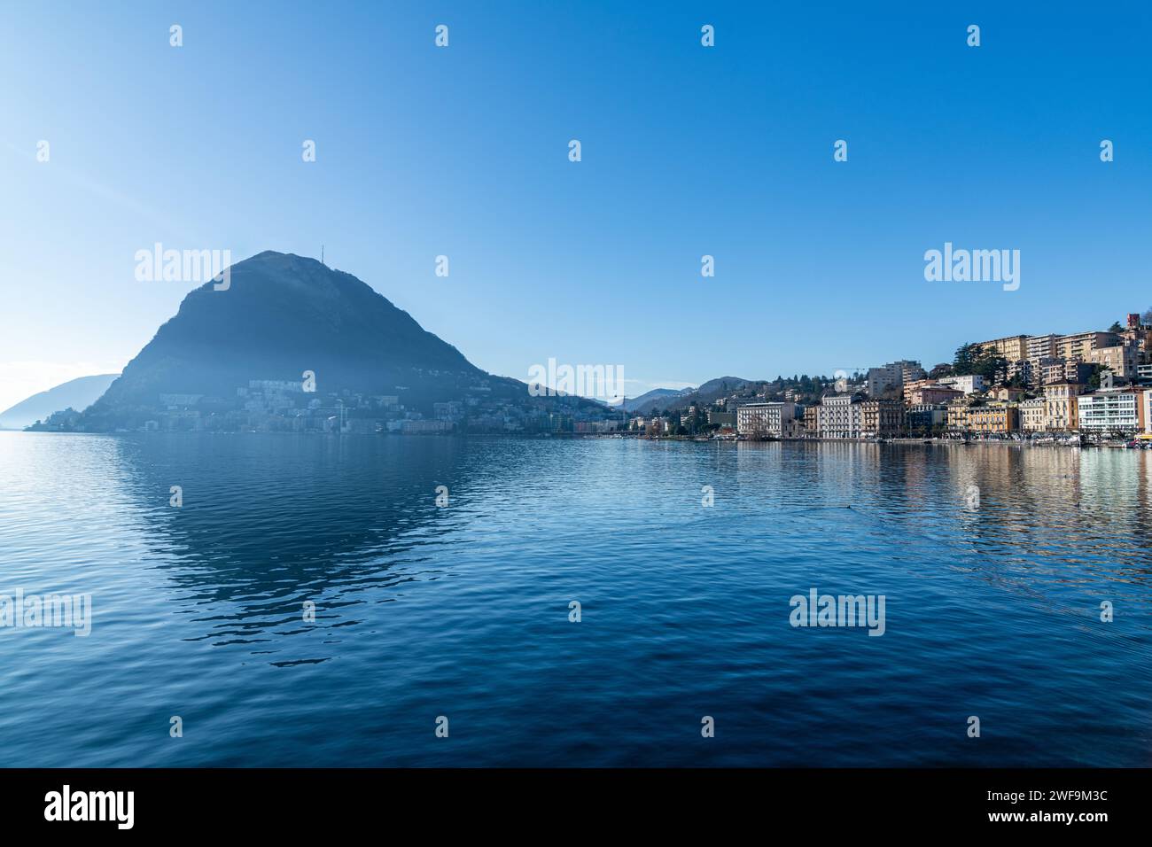 A view of buildings reflected in the water of Lake Lugano in Switzerland Stock Photo