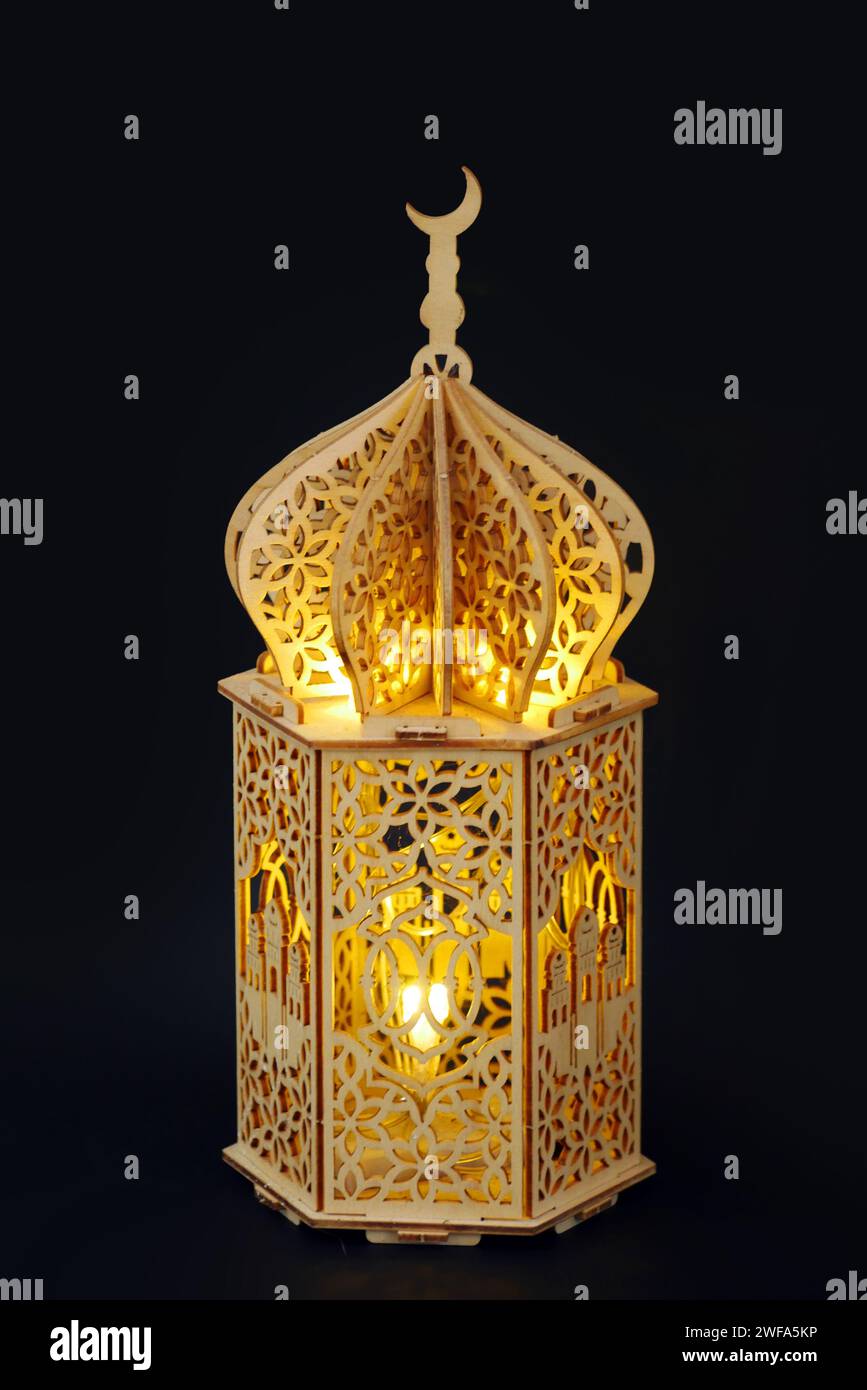 Golden shining wooden Ramadan lantern with Islamic carvings on a dark ...
