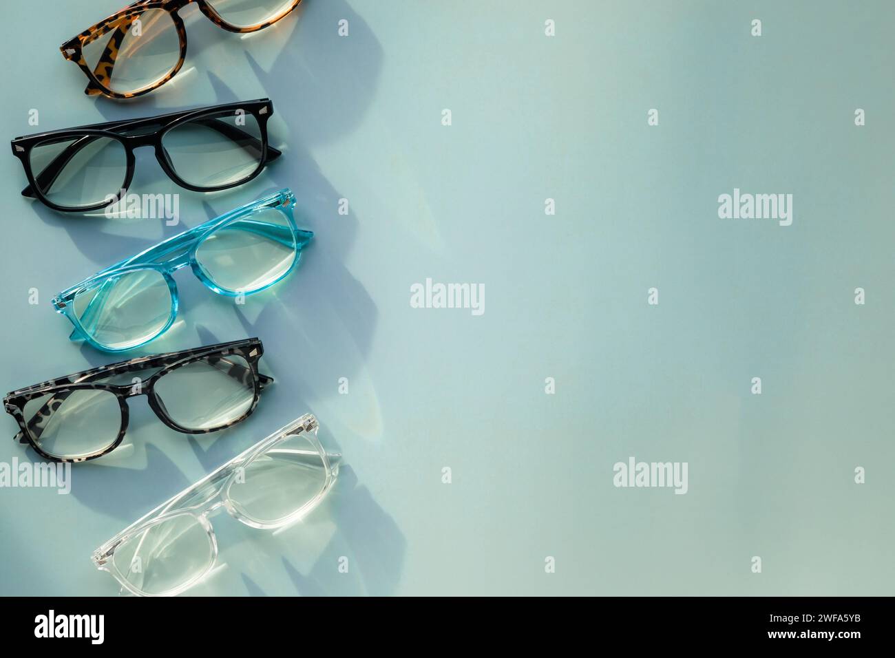 An Assortment of Blue Light Blocking Reading Glasses on Light Blue Solid Background with Copy Space Stock Photo