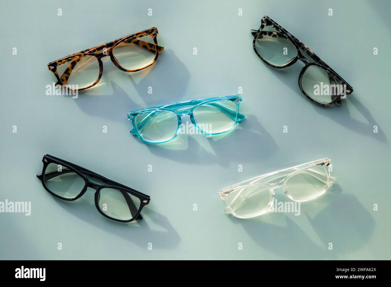An Assortment of Blue Light Blocking Reading Glasses on Light Blue Solid Background Stock Photo