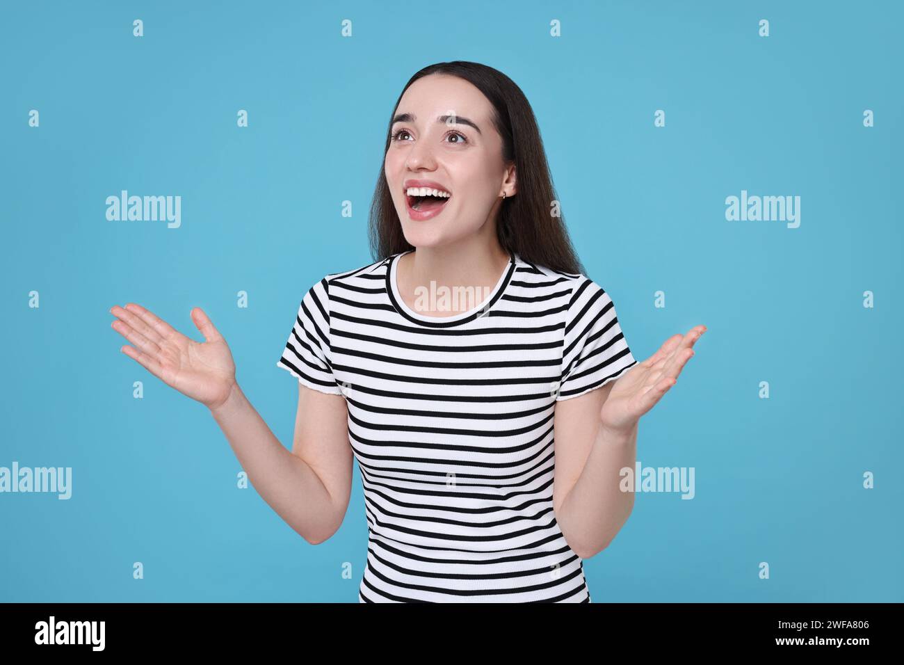 Portrait of happy surprised woman on light blue background Stock Photo ...