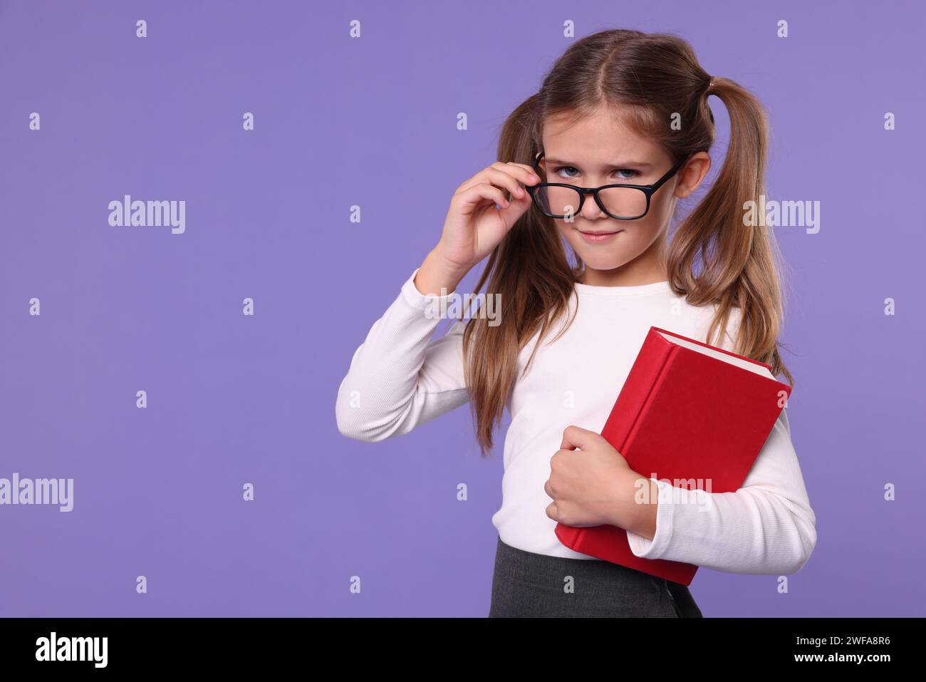Cute schoolgirl with book on violet background. Space for text Stock ...