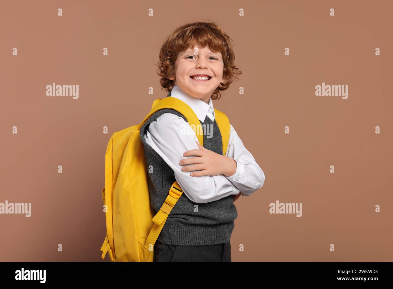 Happy schoolboy with backpack on brown background Stock Photo - Alamy