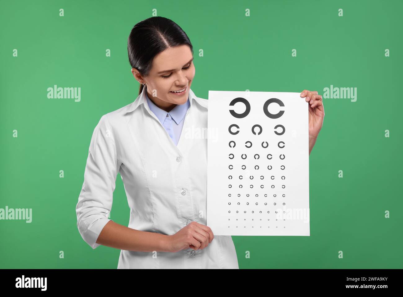 Ophthalmologist with vision test chart on green background Stock Photo