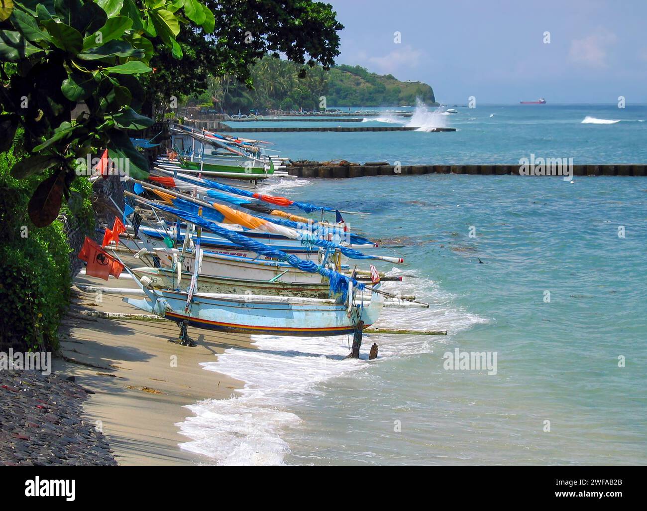 Traditional wooden Balinese fishing boats lined up on the beach at Candidasa or Candi Dasa in Bali, Indonesia. Stock Photo