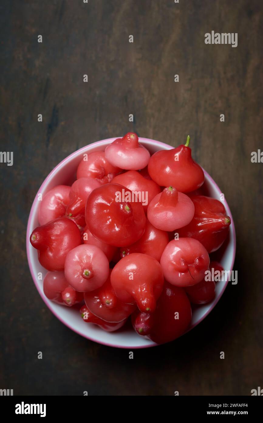 jambu or rose apple, aka bell fruit or wax apple, flesh is crisp and watery, bell-like or pear shaped juicy fruits on rustic wooden table top Stock Photo