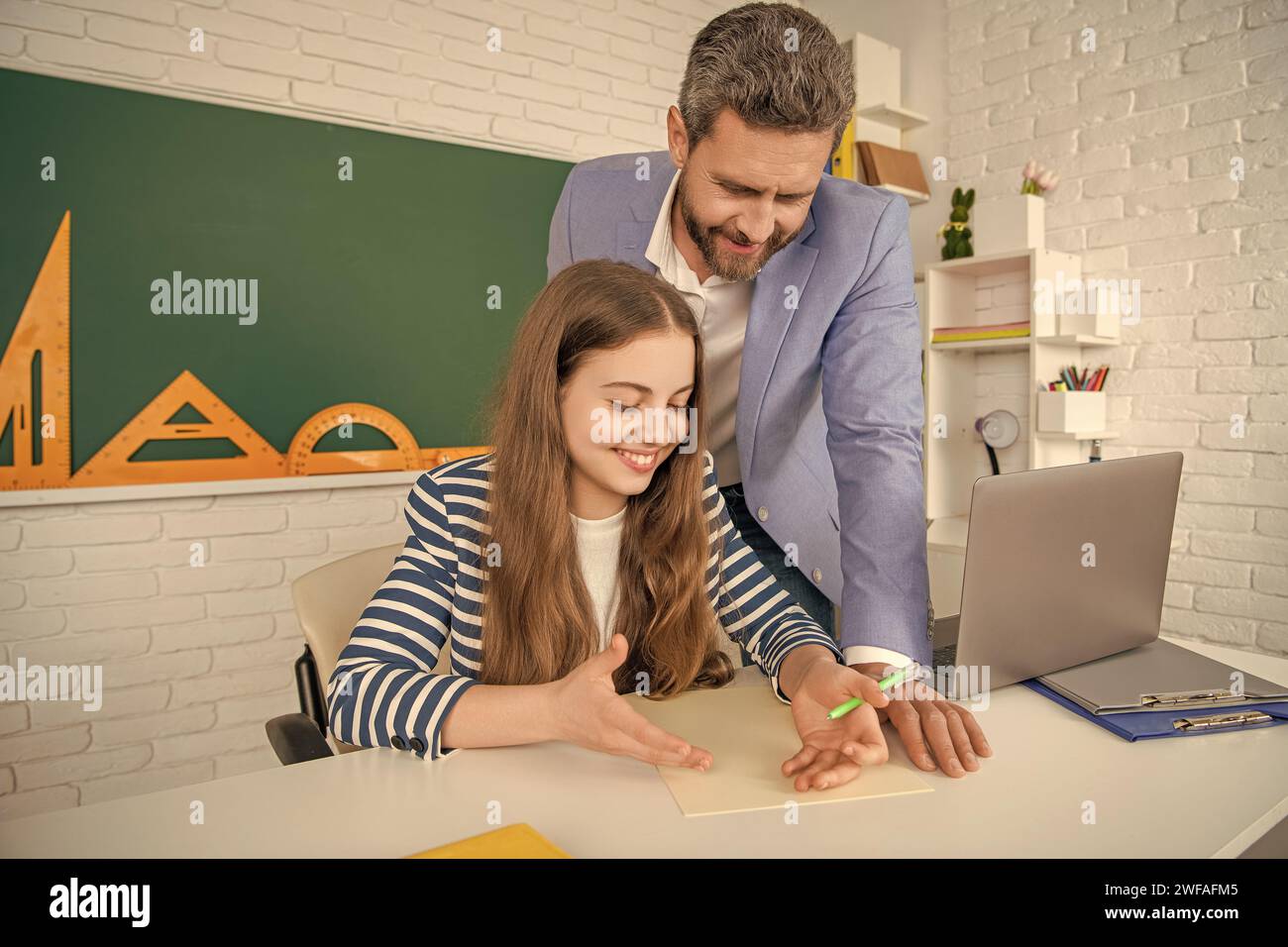 positive girl with teacher in classroom use laptop Stock Photo - Alamy