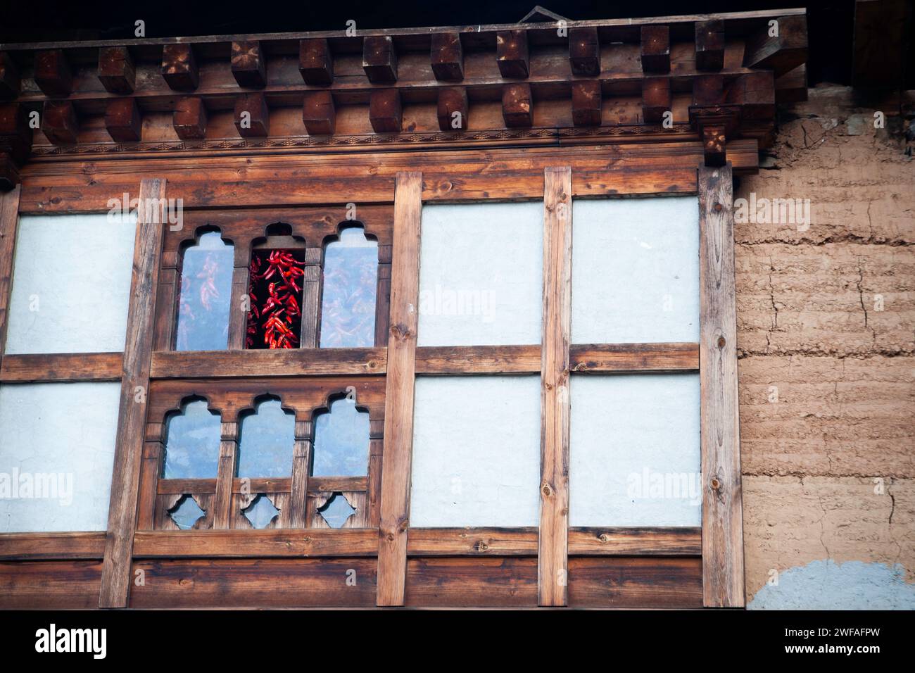Red chili peppers drying indoors hung from rafters as seen through a window of a building, Bhutan, Asia Stock Photo