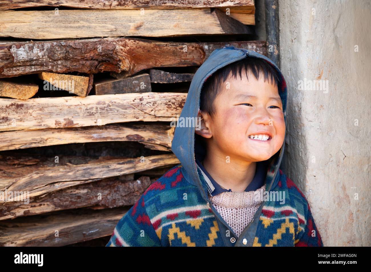 Young Bhutanese boy smiles a cheeky grin outside his home, Ugyen Choling Village, Bhutan, Asia Stock Photo