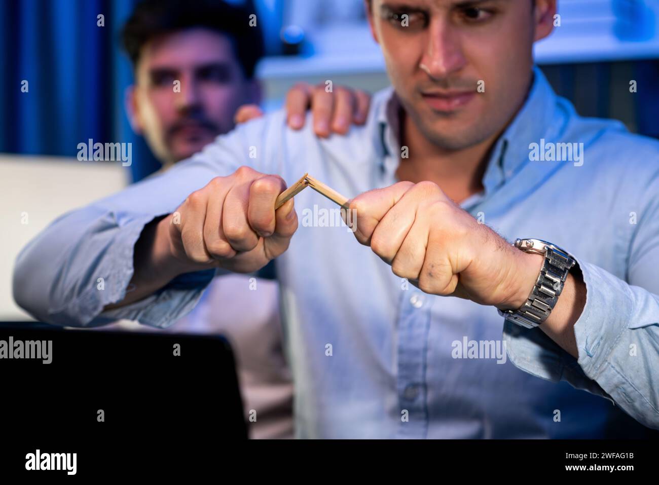 Stressful burnout of businessman destroying pencil for venting emotion in overwork load at night time, supported by business partner to solve issue Stock Photo