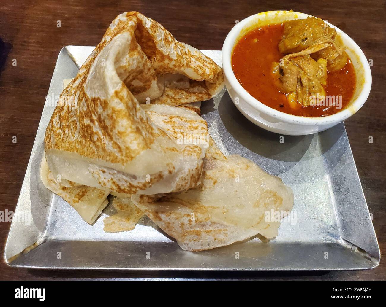 Malaysian pancake, also known as roti canai, with a side of chicken curry in gravy Stock Photo