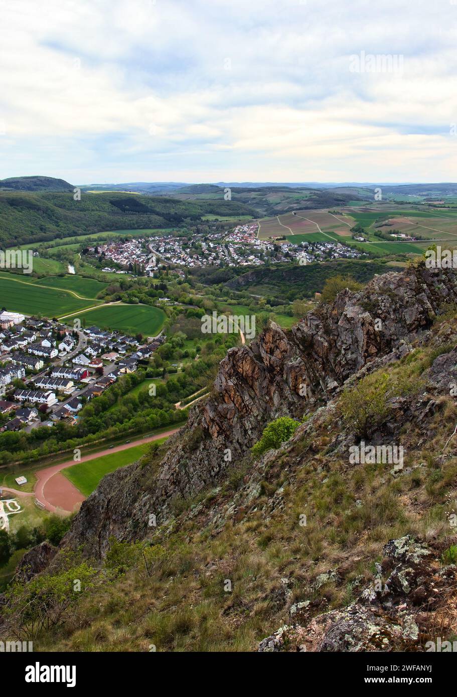 Bad Munster, Germany - May 9, 2021: Jagged edge of Rotenfels cliff overlooking German towns surrounded by green fields. Stock Photo