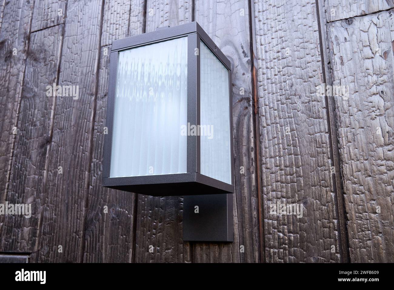 Modern external lamp on burned wood wall Stock Photo