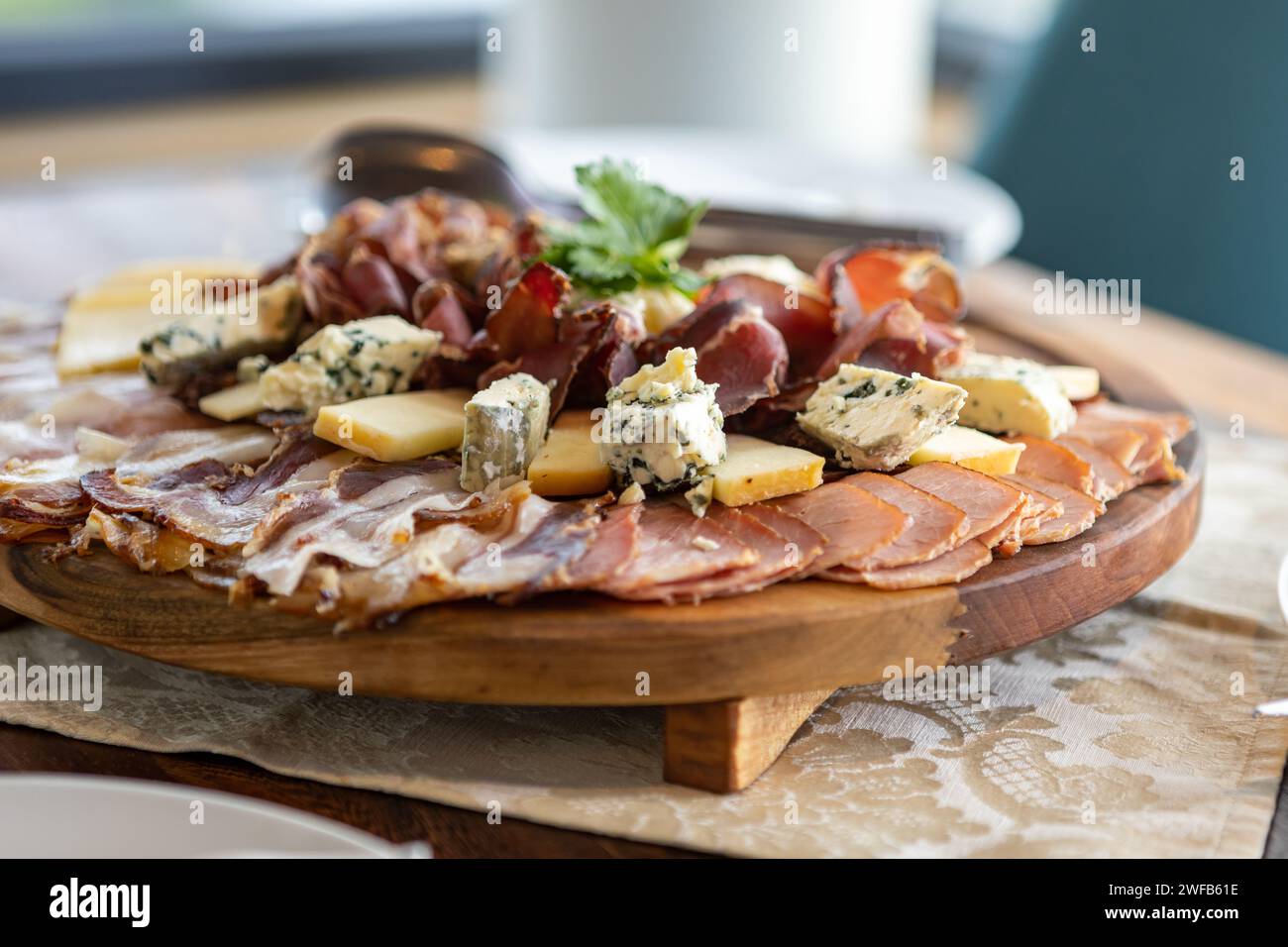A wooden cutting board bearing a delectable arrangement of assorted meats and cheeses. Stock Photo