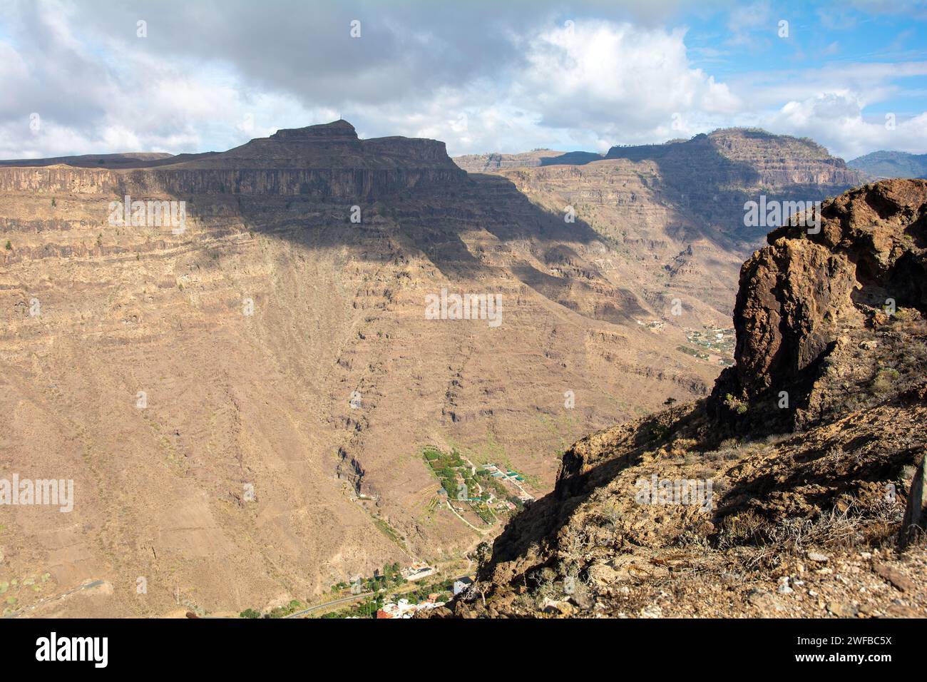Mountains with a small village in the valley on the Canary Island of Gran Canaria in Spain, with blue sky and clouds Stock Photo
