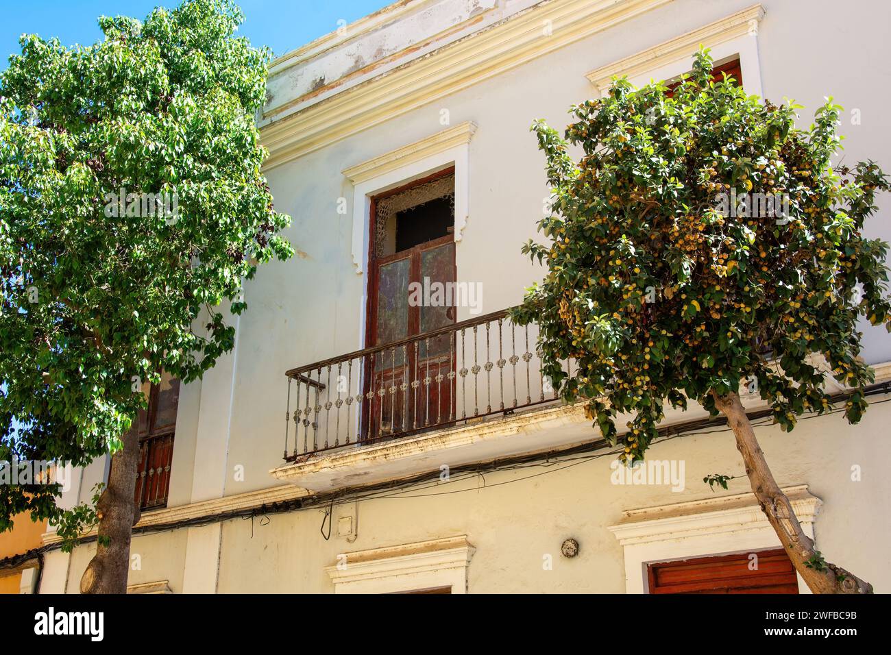 Balcony with a balcony door on an old house in Spain on the Canary Island of Gran Canaria, with trees Stock Photo