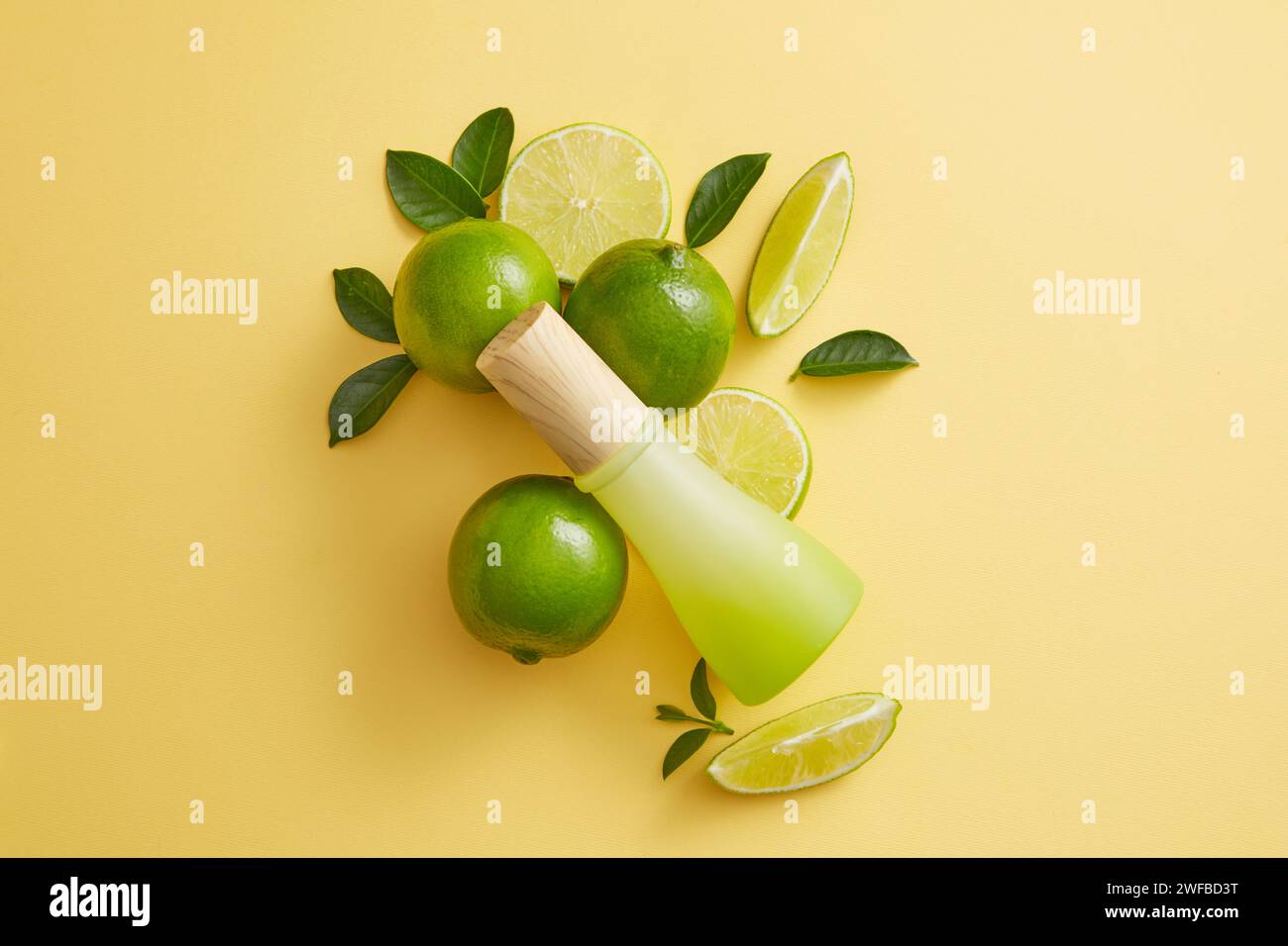 Empty label jar with wooden cap is arranged with Lime and green leaves over light background. Lime (Citrus aurantiifolia) is used to slow down the agi Stock Photo