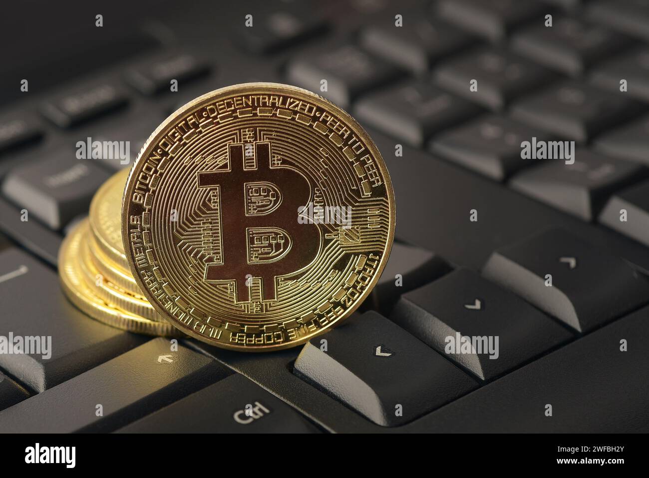 Close up of golden bitcoin on keyboard. Virtual money, mining, blockchain technology concepts. Cryptocurrency. Stock Photo